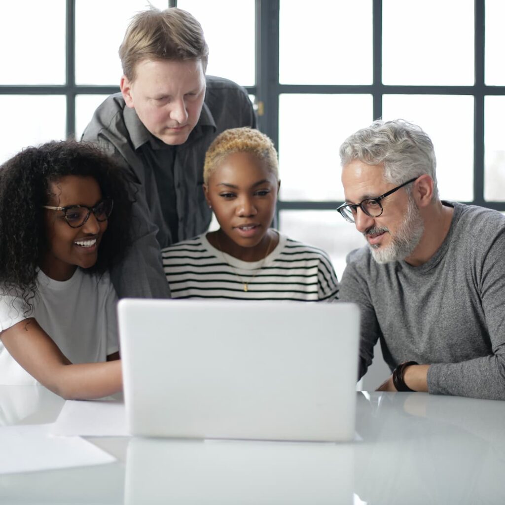 Die Kursteilnehmer sitzen zusammen am Schreibtisch mit einem Laptop. Sie analysieren die Komplexität der Finanzmärkte. Sie sind erleichtert, einen klaren Weg in den Finanzmärkten zu finden.